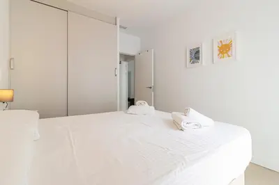 a white bedroom with a large white bed with towels on it at Allo Apartments San Clemente Parking Piscina Centro 2 Habitaciones in Jerez de la Frontera