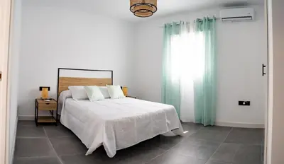 a white bedroom with a bed and a window at Domus Gades in Chiclana de la Frontera