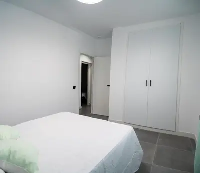 a white bedroom with a bed and a closet at Domus Gades in Chiclana de la Frontera