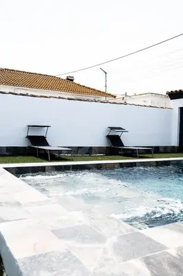 a swimming pool next to a white building at Domus Gades in Chiclana de la Frontera