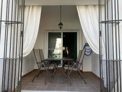a table and chairs on a balcony with curtains at Apartamento a pie de playa in Rota