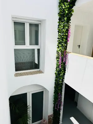 a white building with a window with purple flowers at SOTAVENTO Salmarina in Sanlúcar de Barrameda
