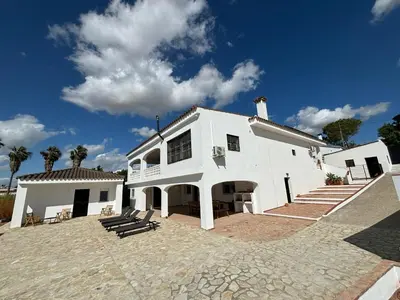 a white building with benches in front of it at Casa Santos Arcos vistas y parking privado in Arcos de la Frontera