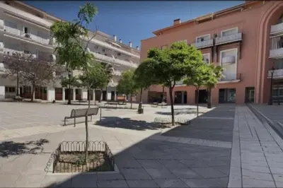 a courtyard with benches and trees in front of a building at Apartamento, Plaza las Infantas in Sanlúcar de Barrameda