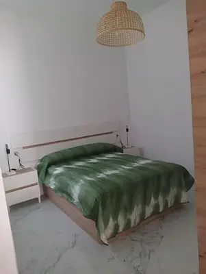 a bed with a green comforter in a room at Apartamento, Plaza las Infantas in Sanlúcar de Barrameda