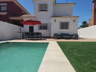 a house with a swimming pool and a table with an umbrella at CHICLANA&DISFRUTA in Chiclana de la Frontera