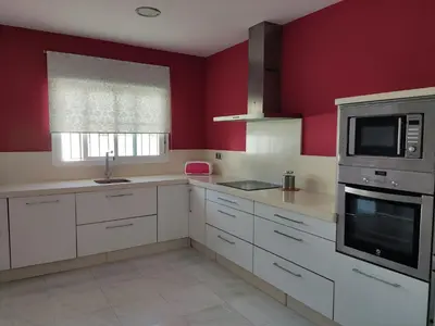 a kitchen with white cabinets and red walls at CHICLANA&DISFRUTA in Chiclana de la Frontera