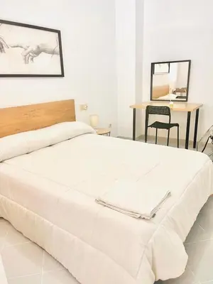 a bedroom with a large white bed and a table at PISO CENTRO HISTÓRICO 3 DORMITORIOS in Jerez de la Frontera
