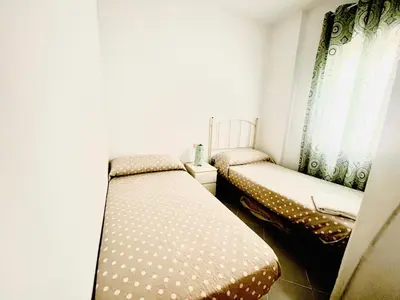a small room with two beds and a window at PISO CENTRO HISTÓRICO 3 DORMITORIOS in Jerez de la Frontera