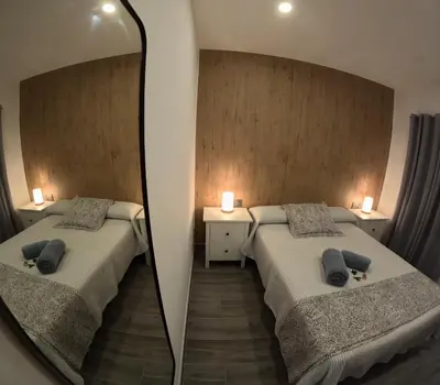 a mirror reflecting a bedroom with two beds at El rincon de Carmen in Jerez de la Frontera