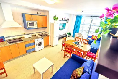 a living room with a blue couch and a kitchen at Mercado Abastos Central Apartment in El Puerto de Santa María