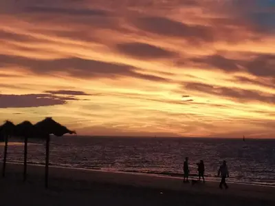 a group of people walking on the beach at sunset at Fortes holidays in Sanlúcar de Barrameda