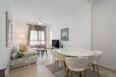 a white living room with a table and a couch at Maravilloso apartamento junto al mar a 5 km Cadiz in Puerto Real