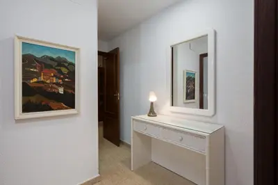 a white dressing table with a mirror and a painting at Maravilloso apartamento junto al mar a 5 km Cadiz in Puerto Real