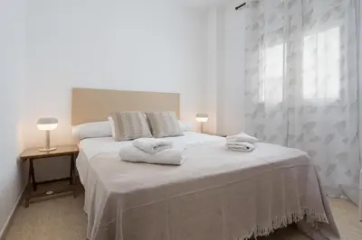 a white bedroom with a bed with towels on it at Maravilloso apartamento junto al mar a 5 km Cadiz in Puerto Real