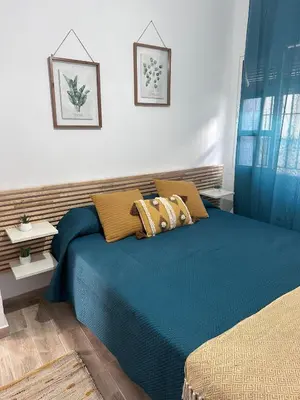 a bedroom with a bed with blue sheets and pillows at TORREJÓN in Jerez de la Frontera