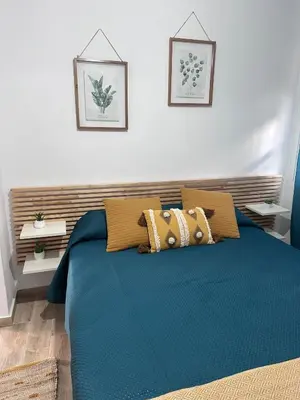 a bedroom with a bed with blue sheets and pillows at TORREJÓN in Jerez de la Frontera