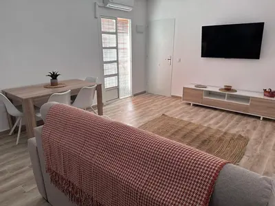 a living room with a table and a tv on a wall at TORREJÓN in Jerez de la Frontera