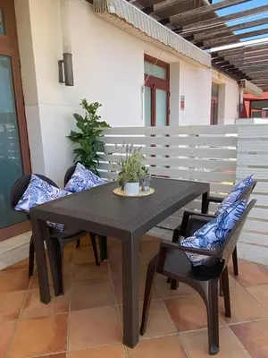 a black table with two chairs and a plant on it at Apartamento Barrosa Beach in Chiclana de la Frontera