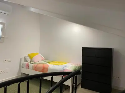 a small bedroom with a bed and a dresser at Apartamento Barrosa Beach in Chiclana de la Frontera
