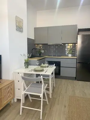 a white kitchen with a table and a refrigerator at Apartamento Barrosa Beach in Chiclana de la Frontera