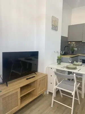 a living room with a tv and a table with a chair at Apartamento Barrosa Beach in Chiclana de la Frontera