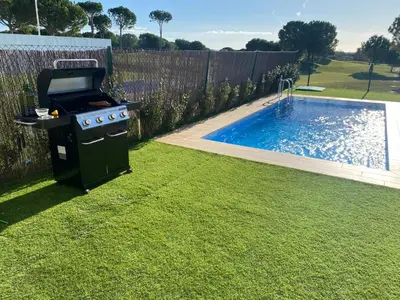 a barbecue grill in a yard next to a swimming pool at Cadiz Golf & Beach in Barrio de Jarana