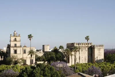 an old castle with palm trees and purple flowers at La Baraka Apartamentos 2 in Jerez de la Frontera