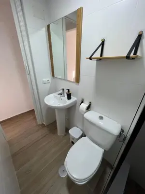 a white bathroom with a toilet and a sink at Apartamento de Encanto in San Fernando