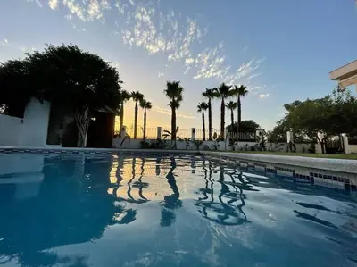 a large swimming pool with palm trees in the background at Sunset Villa Arcos in Arcos de la Frontera