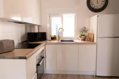 a kitchen with white cabinets and a white refrigerator at Casa Amelí by Gades Gestión in Cádiz