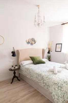 a white bedroom with a bed and a chandelier at Casa Amelí by Gades Gestión in Cádiz