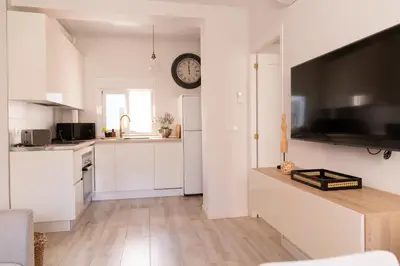 a kitchen with white cabinets and a clock on the wall at Casa Amelí by Gades Gestión in Cádiz