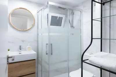 a bathroom with a glass shower and a sink at Falla Suite Bajo in Cádiz