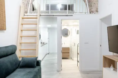 a living room with a couch and a staircase at Falla Suite Bajo in Cádiz