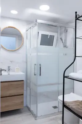 a bathroom with a glass shower and a sink at Falla Suite Bajo in Cádiz