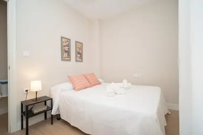 a white bedroom with a white bed with pink pillows at Sibs Sanlucar Maestrante Centrico Ideal Familias in Sanlúcar de Barrameda