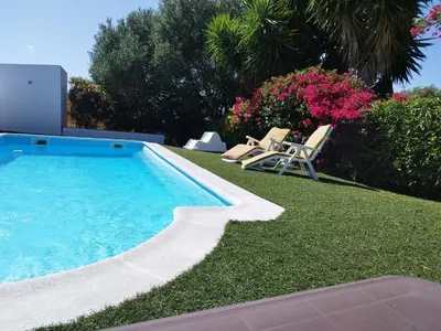a swimming pool in a yard with two lawn chairs at Vivienda Rural Los Madroños in Malcocinado