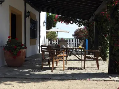 a patio with a table and chairs and an umbrella at Vivienda Rural Los Madroños in Malcocinado