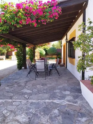 a patio with a table and chairs under a wooden pergola at Vivienda Rural Los Madroños in Malcocinado