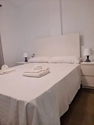 a white bed with two towels on top of it at Apartamento bajo Acuario in Chiclana de la Frontera