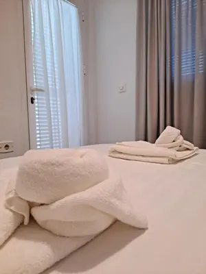 a bedroom with white towels on a bed at Apartamento bajo Acuario in Chiclana de la Frontera