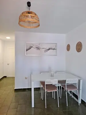 a dining room with a white table and chairs at Apartamento bajo Acuario in Chiclana de la Frontera