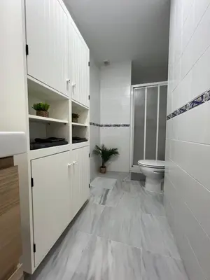 a bathroom with white cabinets and a toilet at Ático con terraza - 2 minutos de la playa in Rota