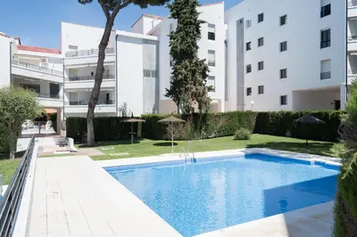 an apartment with a swimming pool in front of a building at Ancora - Piscina & Playa in El Puerto de Santa María