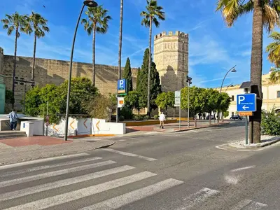 an empty street with a clock tower and palm trees at Apartamento El Tabanco - Ole Solutions in Jerez de la Frontera