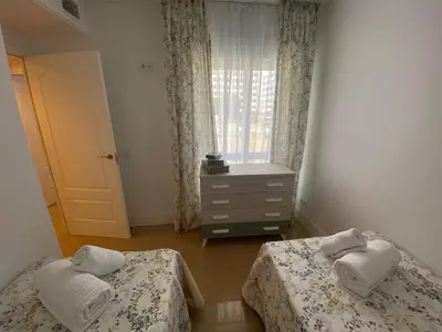 a bedroom with two beds and a dresser and a window at Espectacular Valdemar in El Puerto de Santa María