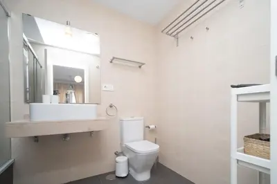 a white bathroom with a toilet and a sink at Calma Beach Bajo de Guía in Sanlúcar de Barrameda