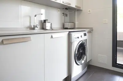 a white kitchen with a washing machine in it at Calma Beach Bajo de Guía in Sanlúcar de Barrameda