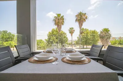 a table with glasses and plates on a table with palm trees at Calma Beach Bajo de Guía in Sanlúcar de Barrameda